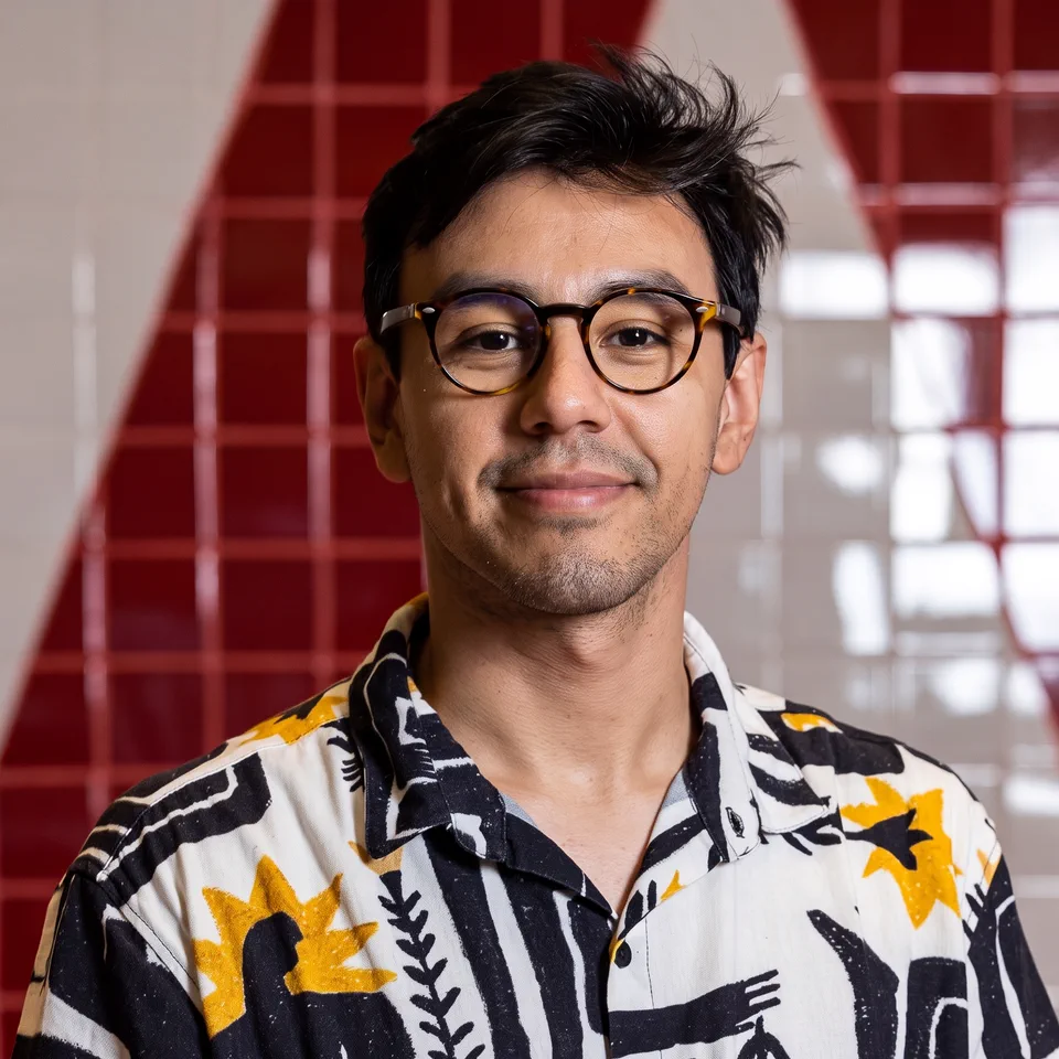 Jonatas Salgado, de óculos e camisa estampada, sorrindo.